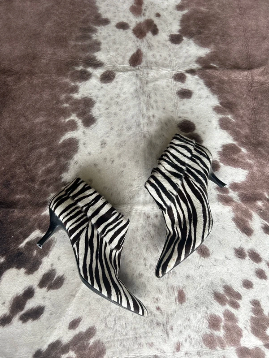 Zebra-striped high-heeled boots on a patterned surface