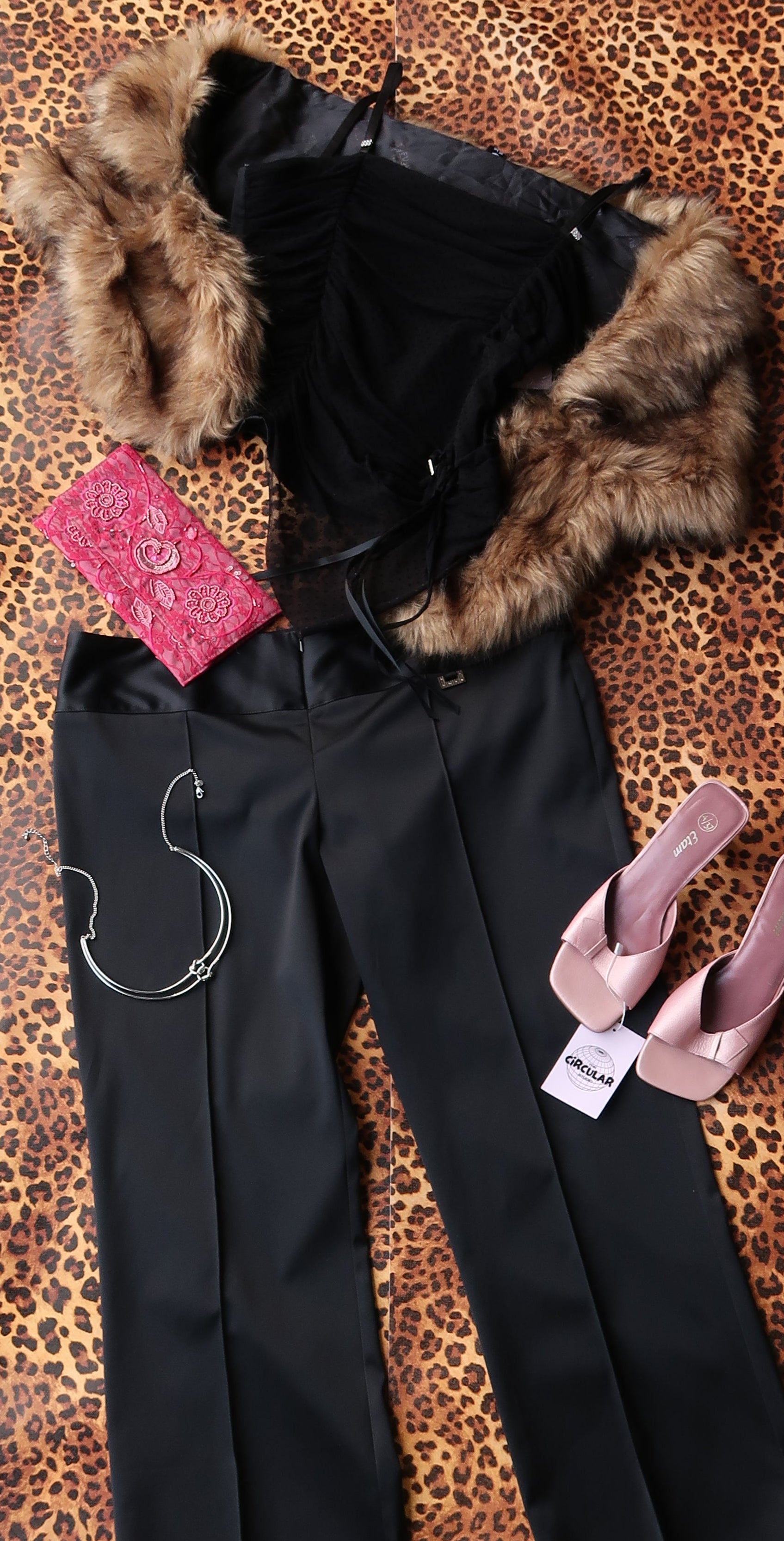 Black pants with fur trim and pink shoes on a leopard print surface