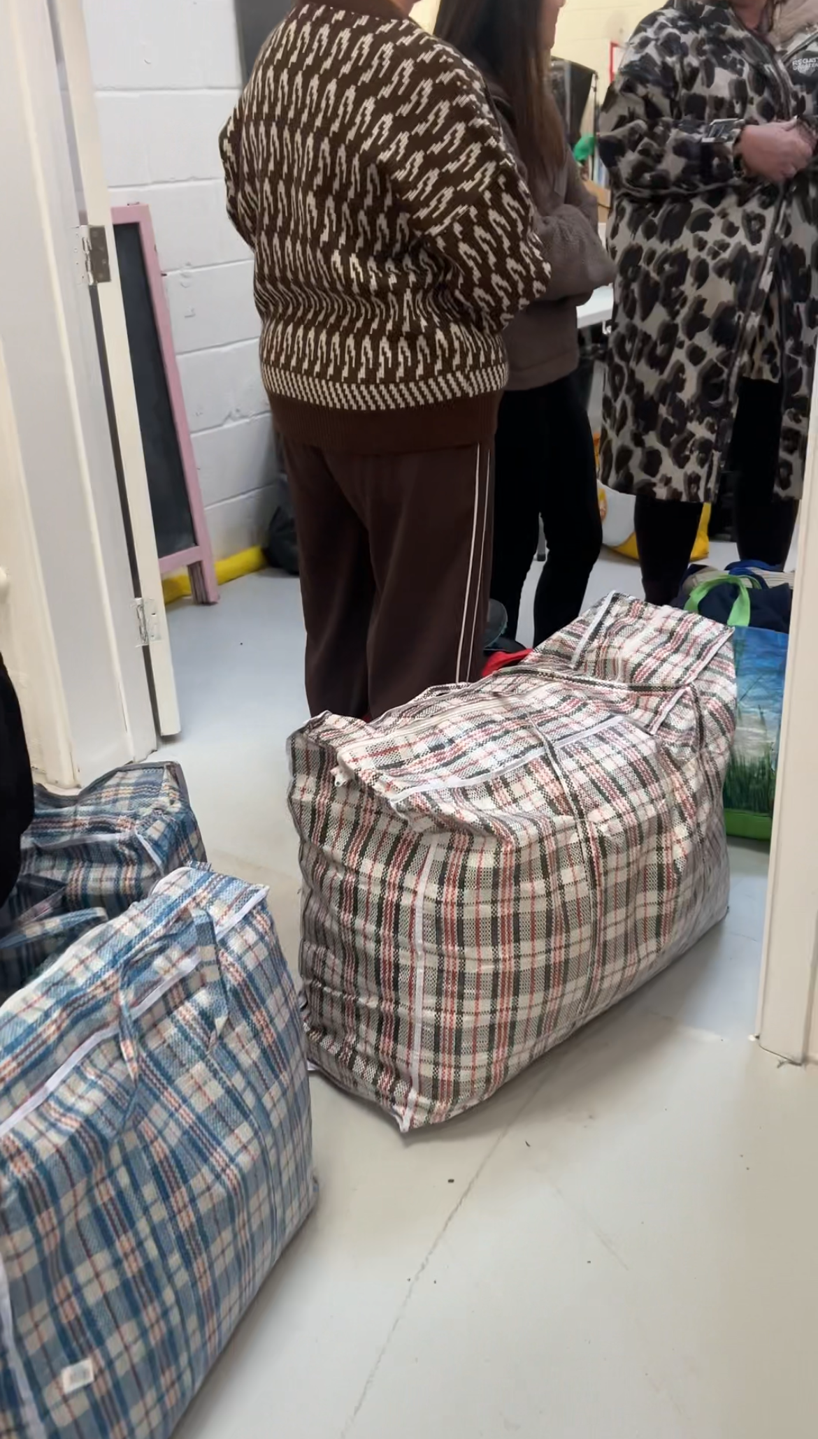 Plaid bags on the floor with people in the background