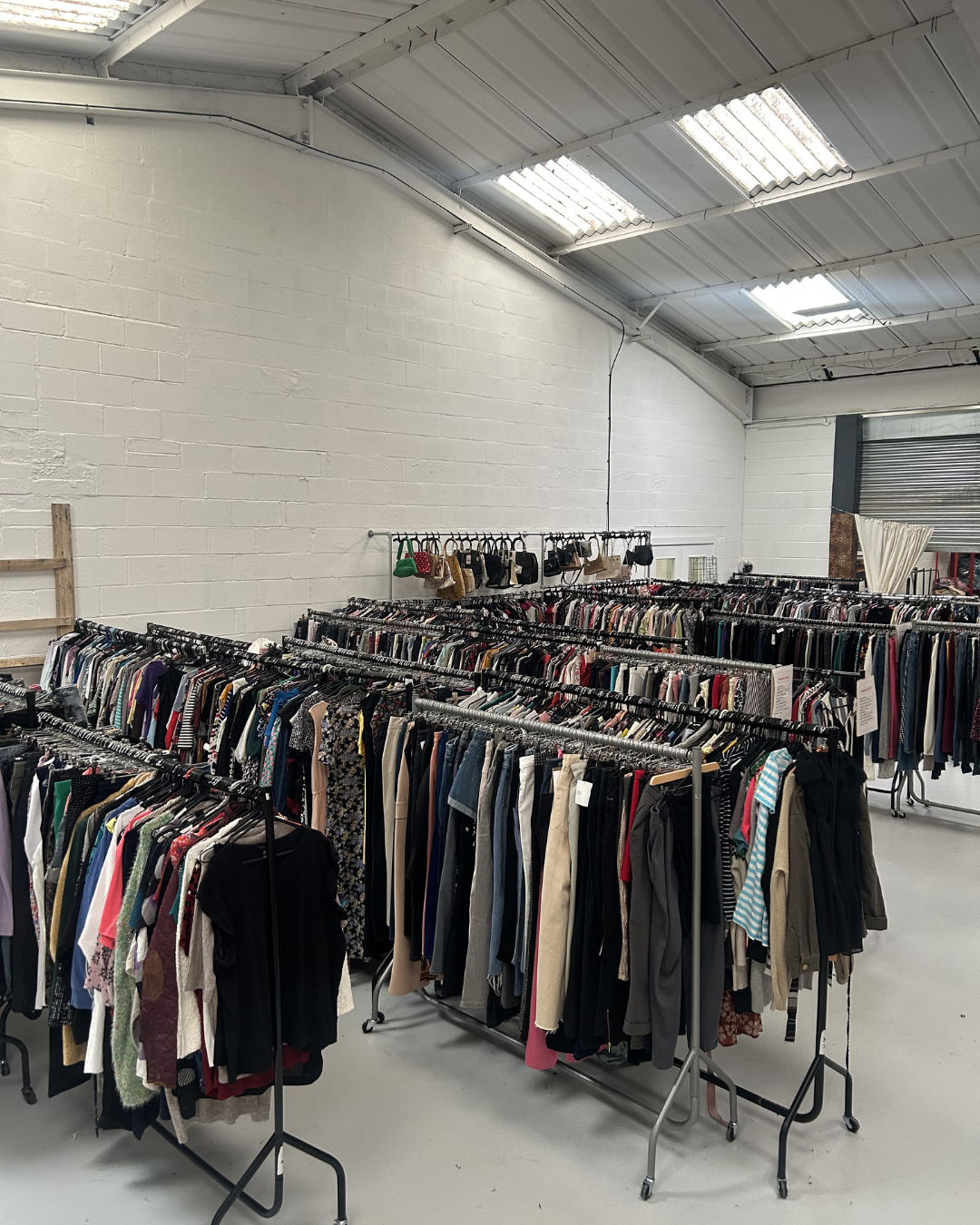 Image of second hand clothing warehouse filled with rails of clothing