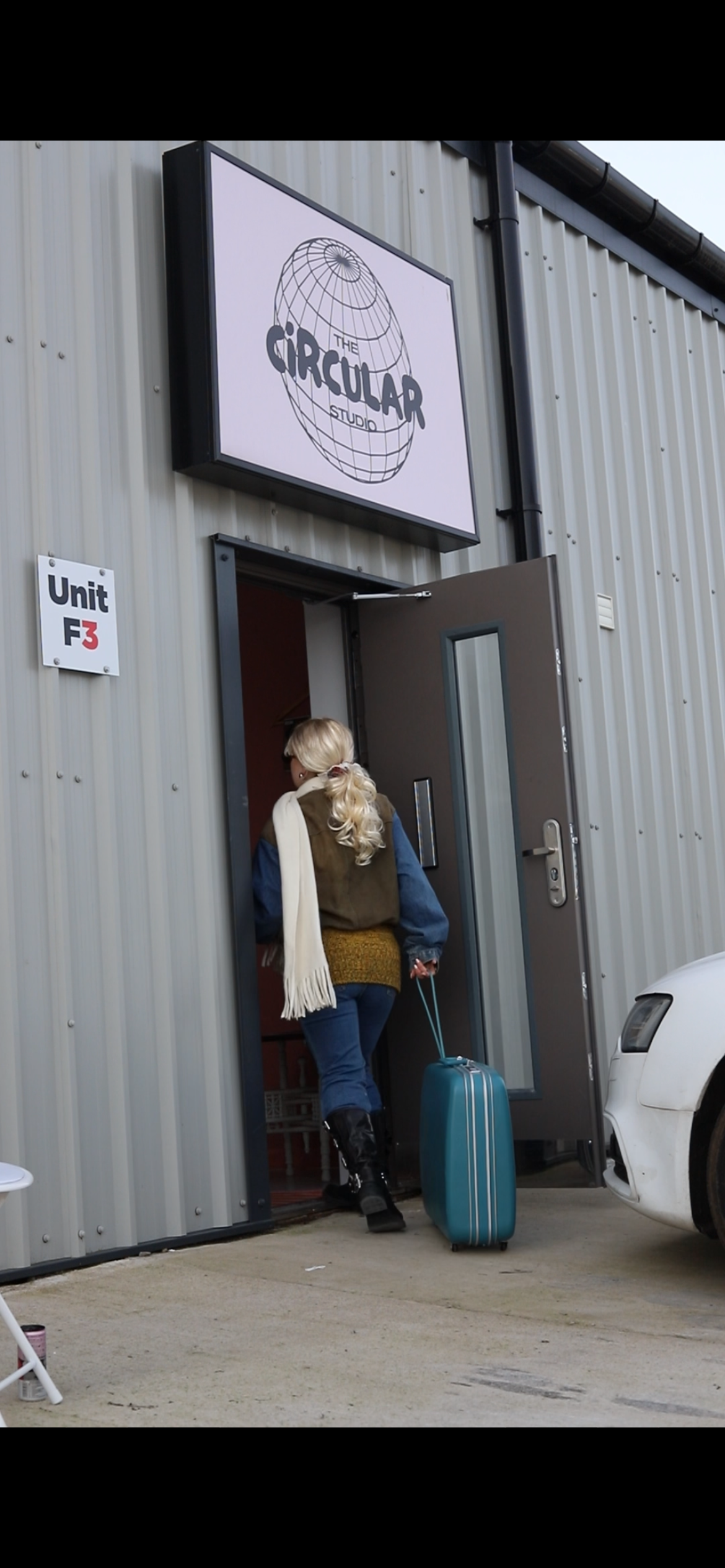 Person with a suitcase exiting a building with 'Circular' branding.